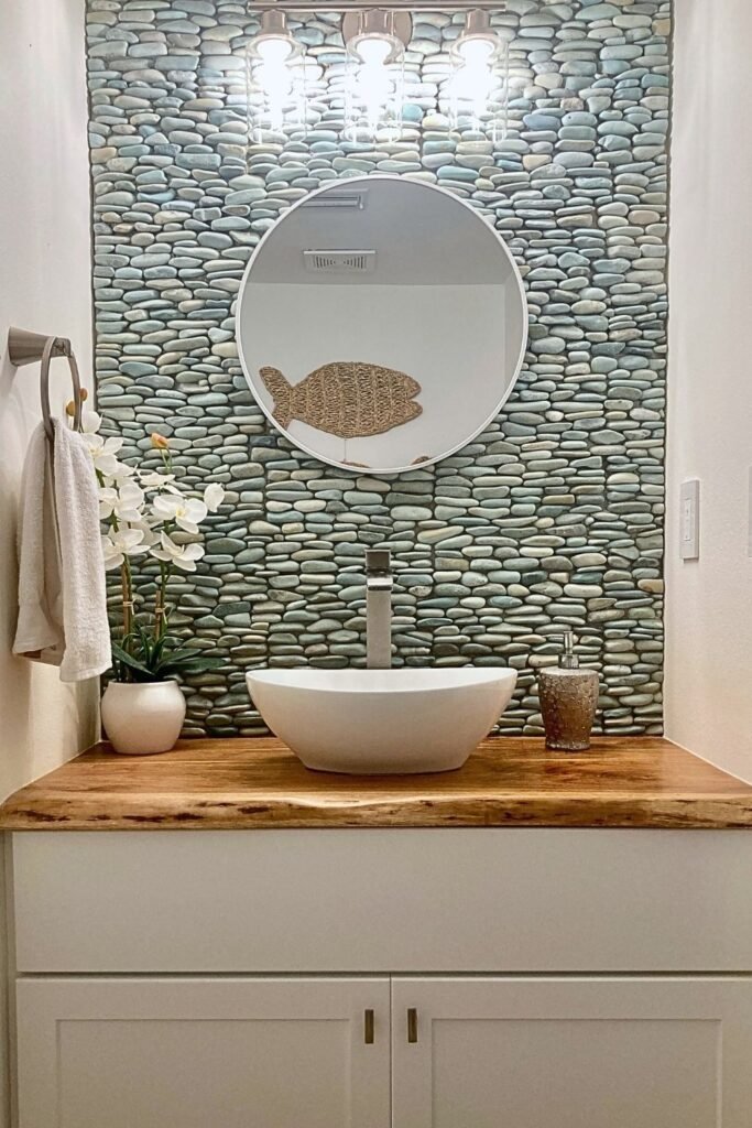 Coastal half bath remodel organic bathroom design with stone wall, vessel sink and live edge wood countertop.